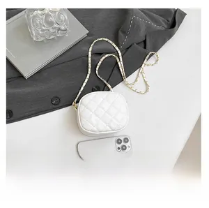 Detailed view of white quilted mini bag with elegant metal chain next to a phone