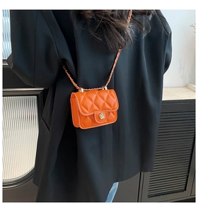 Dettaglio mini borsa trapuntata arancione con fibbia a camelia dorata su blazer nero