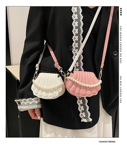 Close-up of shell-shaped crossbody bags with pearl chains in cream and pink finishes