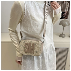 Dettaglio borsa di paglia beige con ricamo floreale e tracolla in tela bianca rinforzata