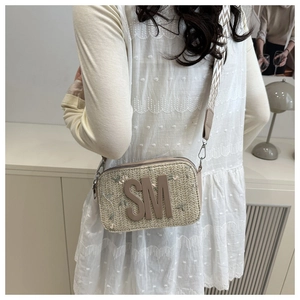 Dettaglio borsa a tracolla in paglia intrecciata con logo SM e tracolla a onde