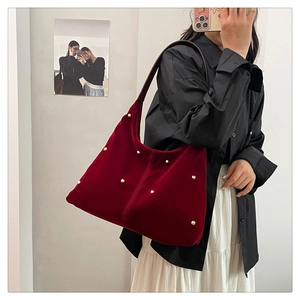 Detail of burgundy velvet hobo bag featuring golden bead studs and soft texture