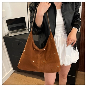 Detail der braunen Wildleder-Hobo-Tasche mit goldenen Nieten und feinen Nähten