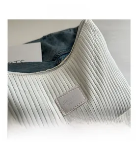 Détail de la texture plissée blanche et du logo en cuir sur ce sac seau élégant