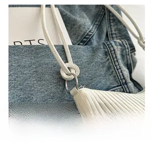 Gros plan sur les anneaux métalliques et la texture plissée du sac à bandoulière blanc