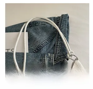 Gros plan d'un sac seau blanc avec des poignées fines et une texture en cuir plissé