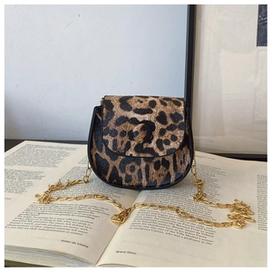 Mini-Umhängetasche mit Leopardenmuster und goldener Kette auf einem Vintage-Buch