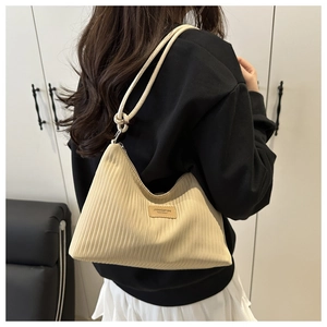 Mannequin portant un sac hobo beige plissé avec bandoulière nouée et écusson