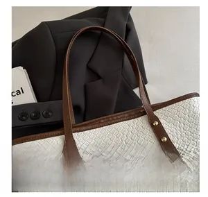 Detail of woven texture on white tote bag with brown leather handle and gold rivet studs