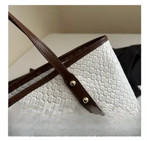 Detailed view of woven texture tote bag featuring golden rivets and brown edge stitching