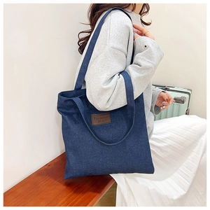 Bolso tote de mezclilla grande con parche de logo en cuero marrón usado por una modelo
