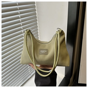 Détail de la texture plissée verticale sur un sac à bandoulière vert clair avec étiquette