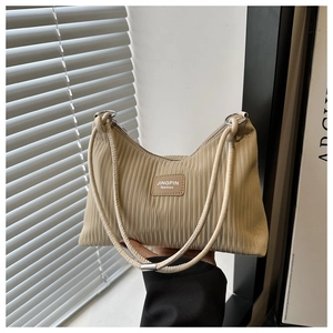Détail du tissu plissé accordéon et de l'écusson logo sur le sac à bandoulière