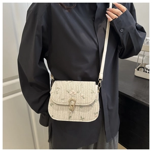 Detail of cream woven crossbody bag with floral embroidery and gold metal clasp