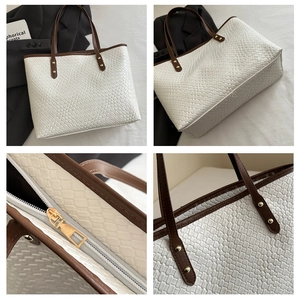 Close-up of white woven tote bag with dark brown handles and golden metal rivets