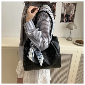 Détail d'un grand sac cabas noir tressé avec un foulard en soie bleu et blanc décoratif