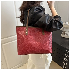 Detail view of woven texture on red tote bag with brown straps and gold rivets