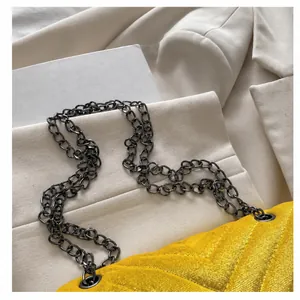 Detail einer gelben Stepptasche mit dunkler Gliederkette auf einem hellen Blazer