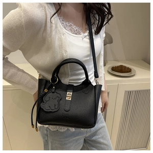 Détail du sac seau noir grainé avec fermoir doré et pendentif en forme de petit chien