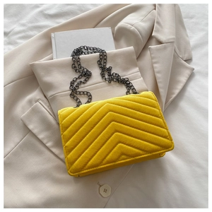 Detail der gelben Samt-Stepptasche mit eleganter V-Steppung und Vintage-Metallkette