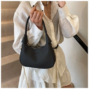 Detail der schwarzen Hobo-Tasche mit Knotengriff und Goldkette an einem Model
