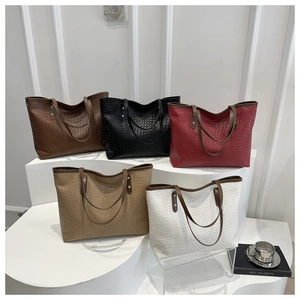 Detailed arrangement of five woven tote bags in various colors on white gallery steps