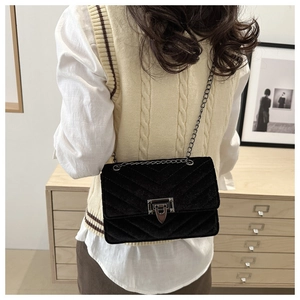 Detail der schwarzen Samt-Stepptasche mit Vintage-Drehverschluss und V-Nähten am Kettenriemen