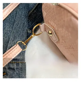 Detailansicht der pinkfarbenen Schlangenmuster-Tasche mit polierten goldenen Metallhaken