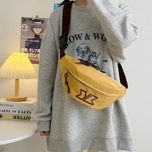 Close-up of mustard yellow crossbody bag featuring brown embroidered logo and adjustable strap