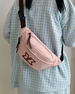 Pink crossbody bag detail featuring embroidered logo and adjustable strap on a plaid shirt