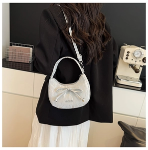 Sac à main croissant argenté métallisé avec nœud et bandoulière réglable porté par modèle