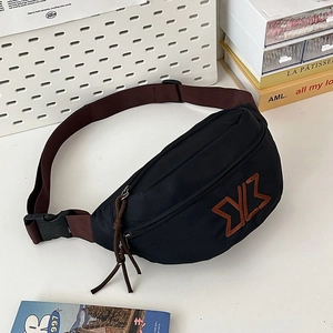 Detail of black crossbody bag with brown geometric embroidery and adjustable wide strap