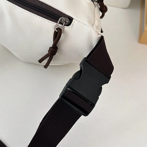 Close-up of durable white canvas chest bag with brown zipper and black plastic buckle