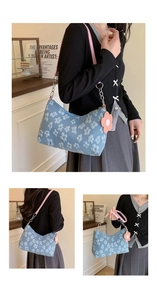 Detail of light blue shoulder bag featuring 3D floral embroidery and pink chain strap
