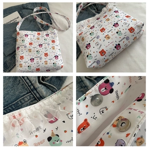 Detail van de witte canvas tas met berenprint, kantafwerking en metalen magneetsluiting