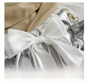 Detail show of metallic silver pleated bag with a large white organza bow decoration