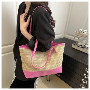 Vue détaillée du sac cabas en paille beige avec finitions rose vif porté par un modèle
