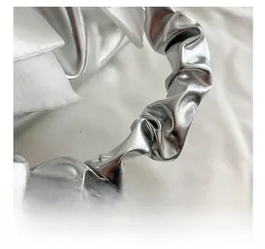 Close-up of metallic silver pleated handle and white satin fabric on fashion handbag