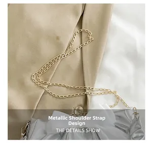 Detail showing the elegant golden chain strap and sheer white bow on the silver shoulder bag