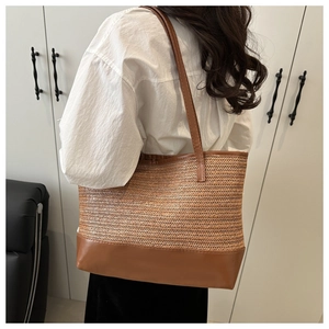 Détail du sac fourre-tout en paille bohème avec bandoulières en cuir marron sur l'épaule