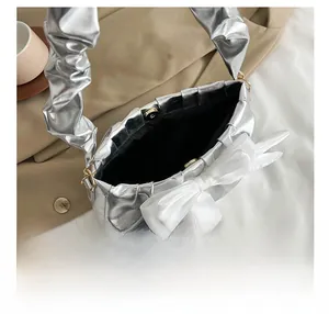 Internal view of silver pleated handbag featuring magnetic closure and large white bow