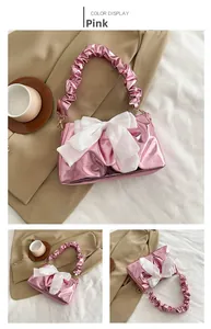 Close-up of metallic pink bag with large white silk bow and ruched scrunchie handle