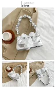 Close-up of a silver handbag featuring a large white chiffon bow and a scrunched handle