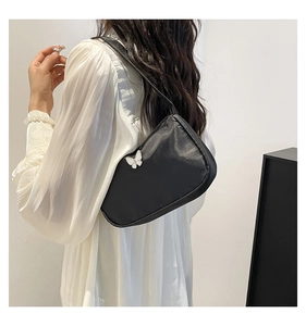 Seitenansicht der schwarzen minimalistischen Achseltasche mit weißer Schleife am Model