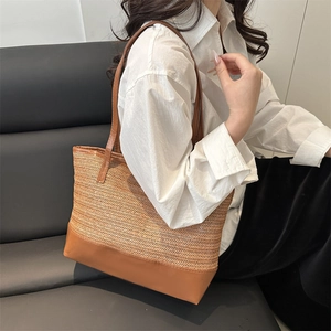 Grand sac cabas en paille avec finitions en cuir marron porté à l'épaule pour l'été