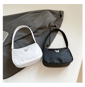 Detailaufnahme von schwarz-weißen Schultertaschen mit metallischen Schmetterlings-Akzenten