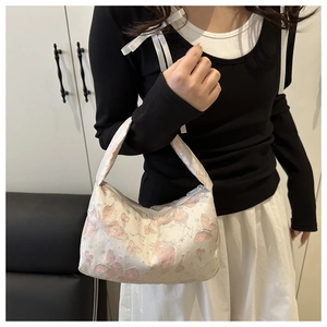 Détail d'un sac à main en satin avec motifs papillon rose et argent et poignée haute