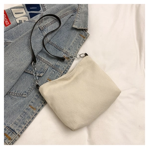 Detail of off-white corduroy bucket bag with black strap and silver chain accent