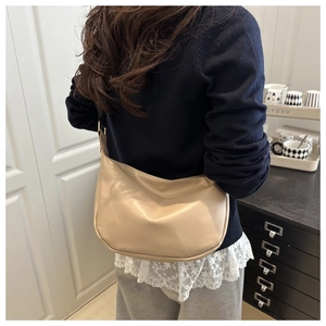 Detail of a minimalist beige crescent tote bag styled with a casual commuting outfit