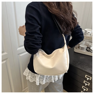Detail of cream hobo bag with Fashion & Bags text and black nylon strap on model
